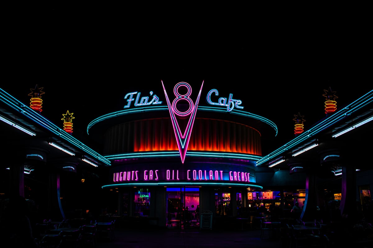 Flo's V8 Cafe glowing in pink and teal neon at night.