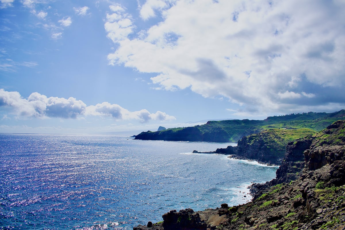 Sunlit cliffs and green headlands stretch along Maui's coastline into sparkling blue water.