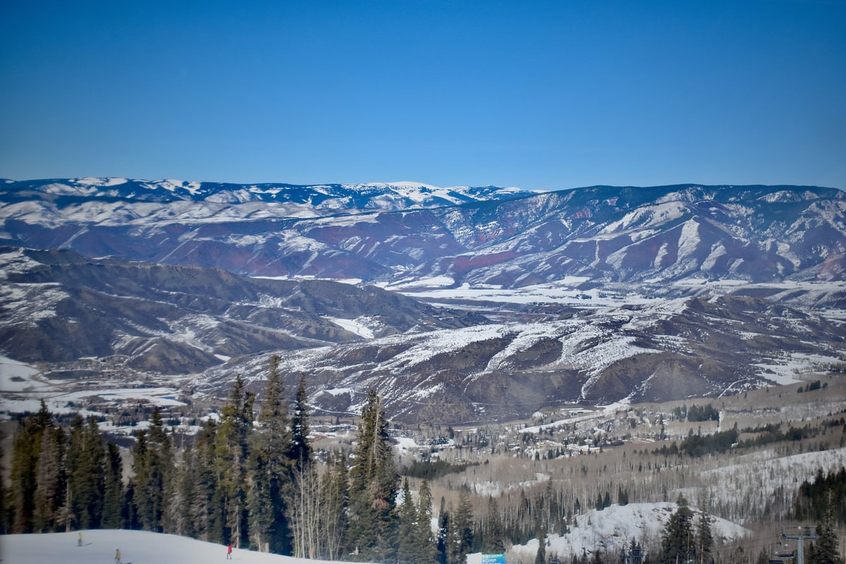 Snow-covered mountains and the valley below Aspen under a blue sky.