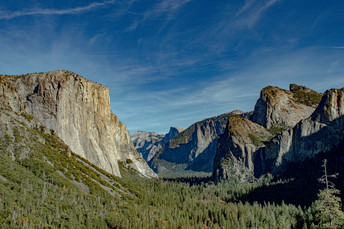 El Capitan and Yosemite Valley stretch out under a streaked blue sky.