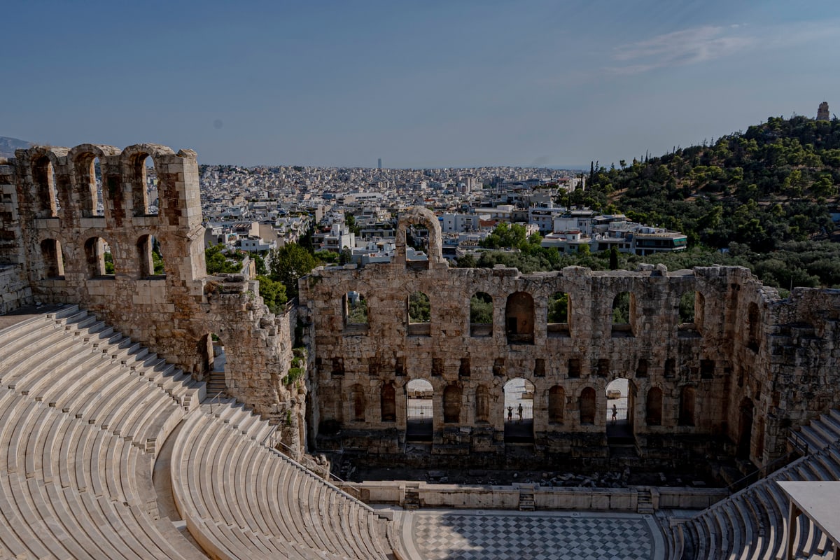 The stone arches and tiered seats of the Odeon of Herodes Atticus with Athens spreading beyond.