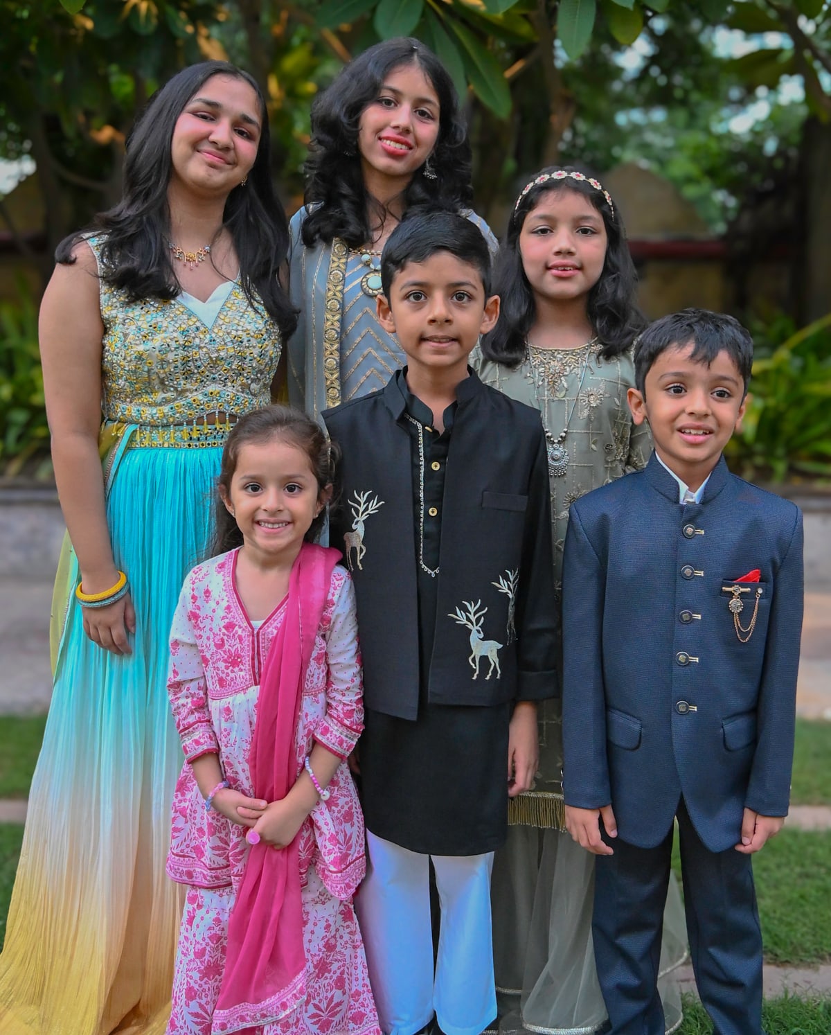 Five young cousins in festive outfits pose together in a garden.