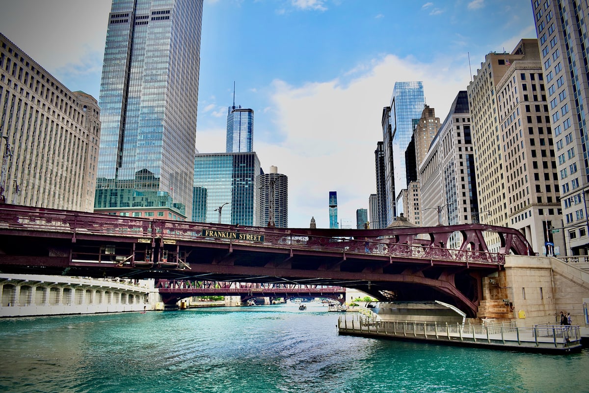 The Franklin Street Bridge over the green Chicago River between skyscrapers.