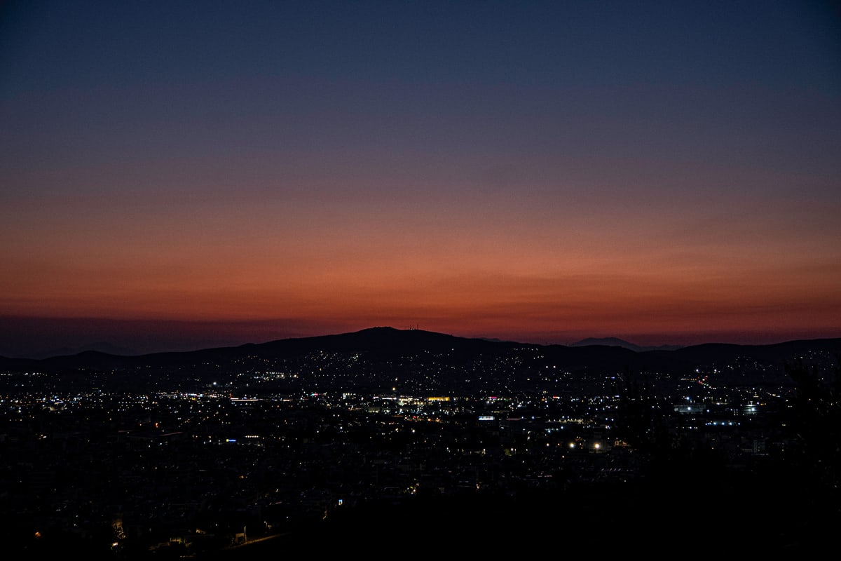 The lights of Athens spread toward the hills under an orange afterglow.