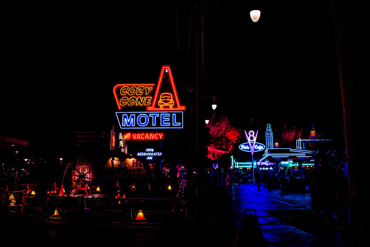 Neon signs light up a street of motels and diners at night.