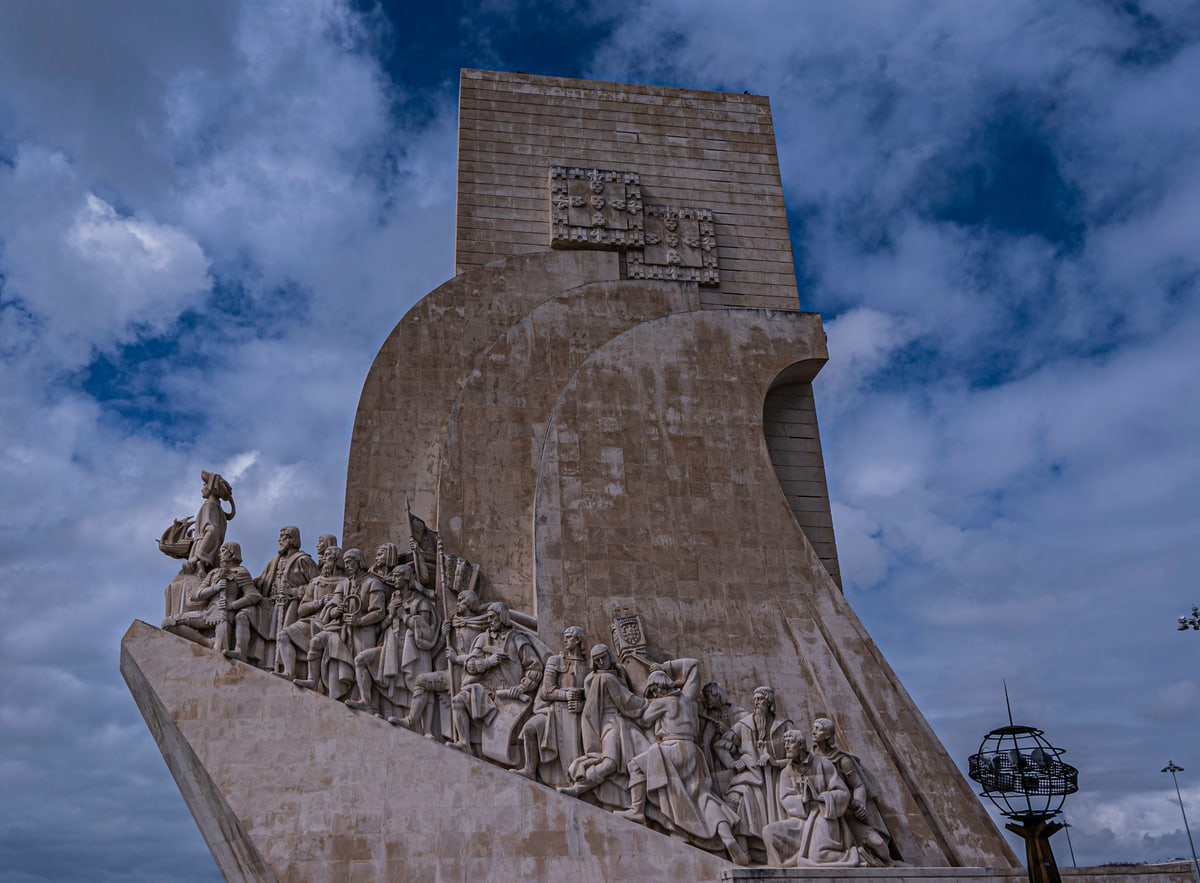The carved stone prow of the Monument to the Discoveries against a cloudy sky.