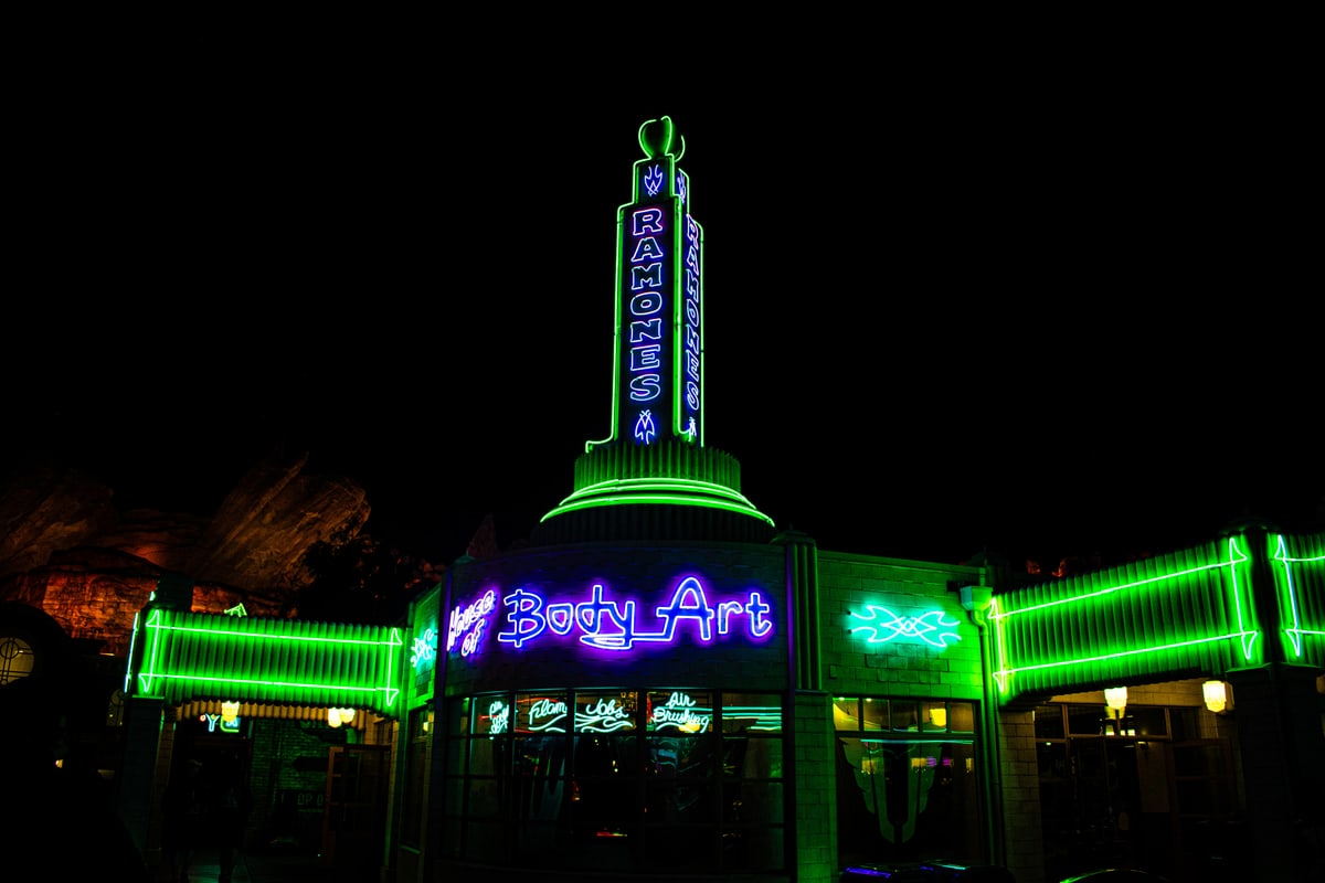 A green neon tower and storefront glowing in the dark.