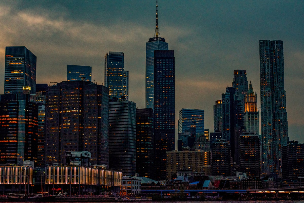 Lower Manhattan towers glow with lit windows at dusk.