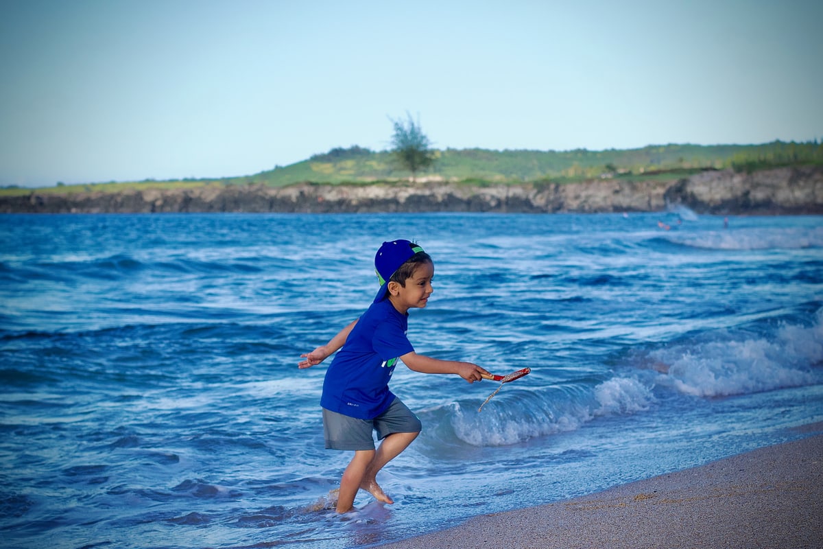 A small boy runs along the water's edge as a wave comes in.