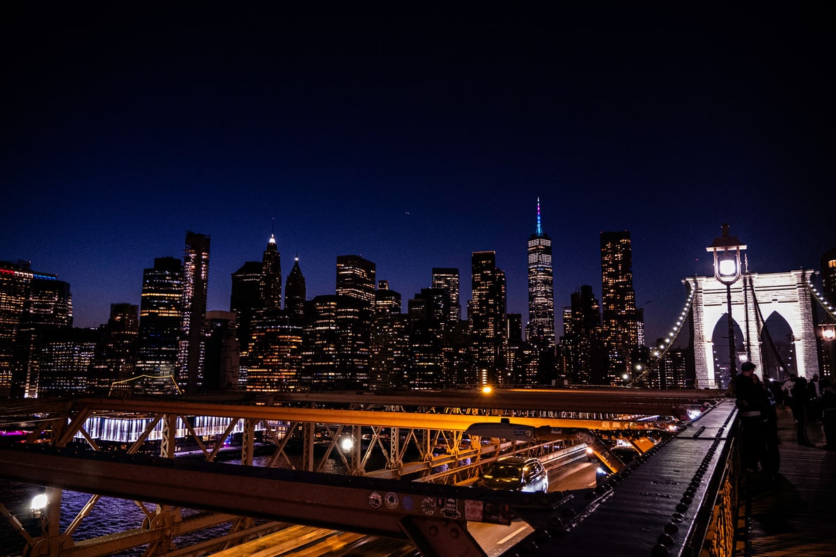 The Brooklyn Bridge and Manhattan skyline glowing at night.