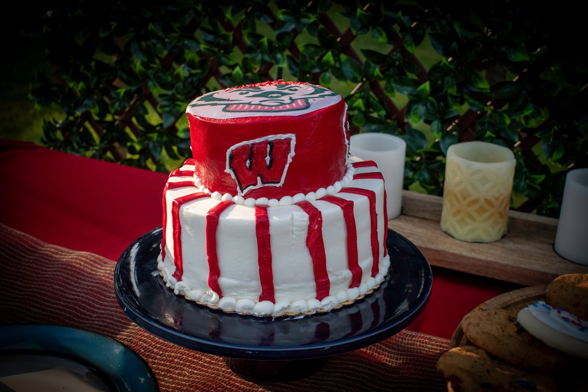 A red and white University of Wisconsin cake on a cake stand.