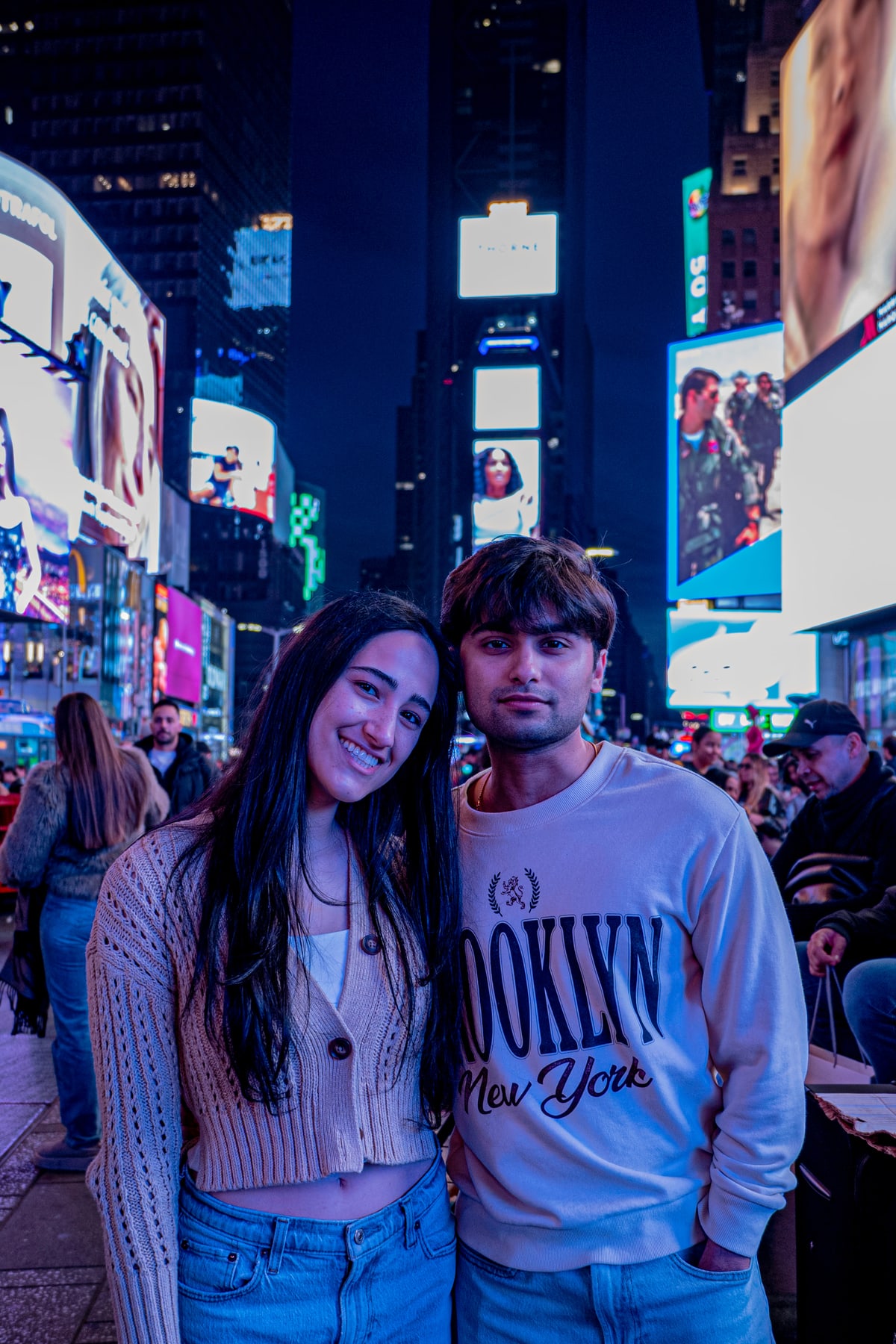 A couple leans together and smiles among the billboards of Times Square.