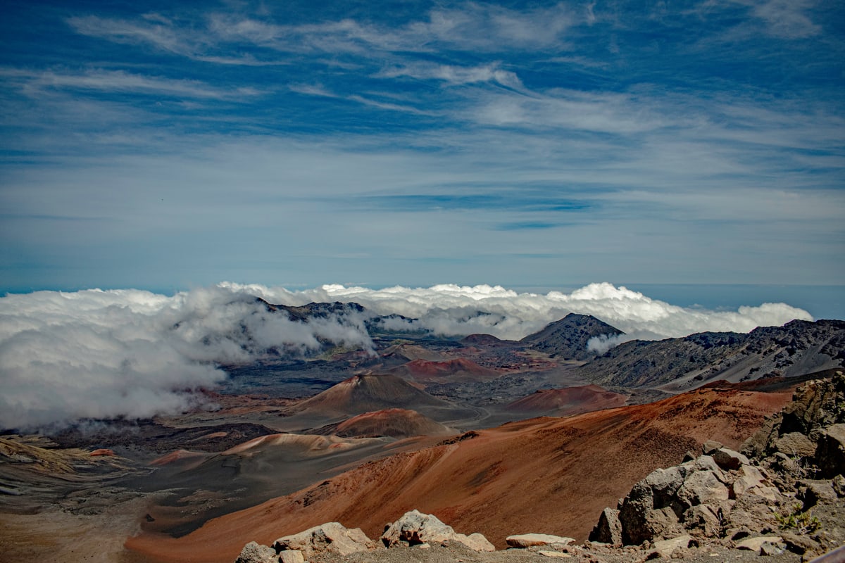 The rust-colored crater of Haleakalā with a sea of clouds beyond the rim.