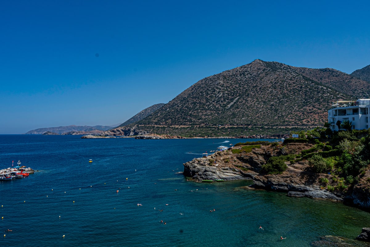A small island harbor with boats beneath a rocky mountain.