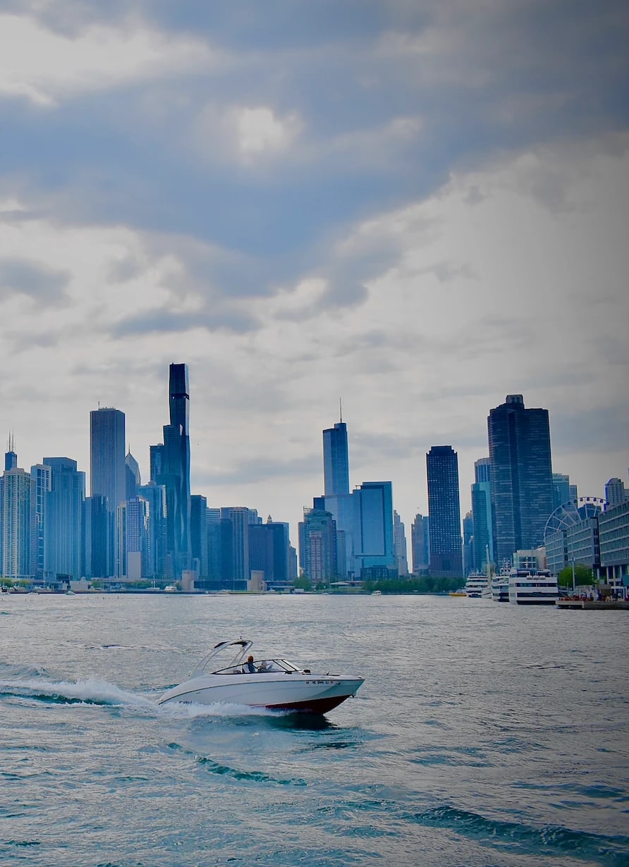 A speedboat crosses Lake Michigan in front of the Chicago skyline under heavy clouds.